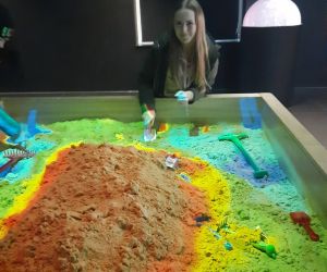 Uczennica przy stole doświadczeń – piasek kinetyczny.