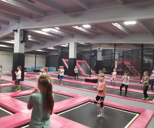 Dzieci pod nadzorem instruktora wykonują rozgrzewkę przed zabawą