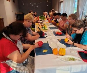 Grupa osób podczas warsztatów, wewnątrz budynku.