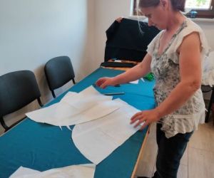 Osoba wykraja ubrania ze wzornika podczas warsztatów z szycia ubrań w stylu BOHO.
