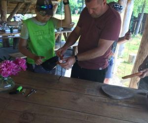 Nauczyciel z uczniem przygotowują kiełbaski do pieczenia w ognisku