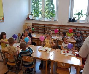 Grupa dzieci 5- i 6-letnich wykonuje doświadczenie z balonikiem.