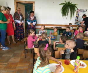 Dzieci jedzą pieczone kiełbaski.