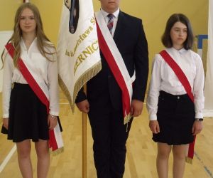 Poczet sztandarowy - chłopiec trzymający sztandar szkoły i dwie dziewczynki z klasy ósmej