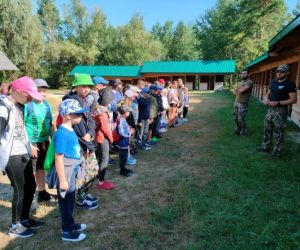 Grupa dzieci wraz z instruktorami podczas zajęć z survivalu, na świeżym powietrzu.