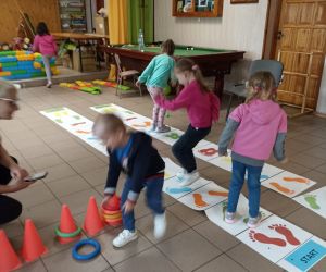 Zdjęcie przedstawia dzieci bawiące się zabawkami animacyjnymi rozłożonymi na podłodze wewnątrz budynku