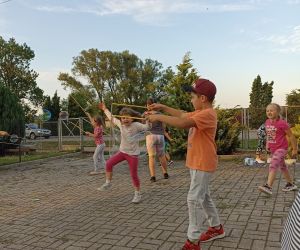 Zdjęcie przedstawia dzieci robiące duże bańki mydlane na świeżym powietrzu.