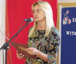 Dyrektor szkoły przemawiająca do uczniów i rodziców na tle biało-czerwonej flagi