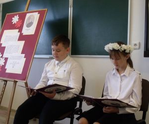 Uczeń i uczennica klasy piątej z wiankiem z kwiatów na głowie czytają teksty ballad Mickiewicza