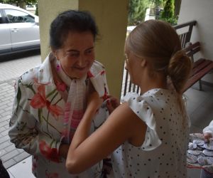 Na zdjęciu widoczne są dwie osoby jedna drugiej zapina plakietkę. 