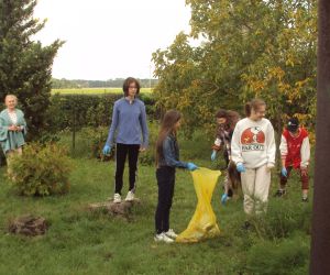 Uczniowie klasy 8 z wychowawczynią zbierają śmieci wokół szkoły.