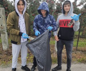 Chłopcy z klasy ósmej zbierają śmieci przy sadach niedaleko szkoły.