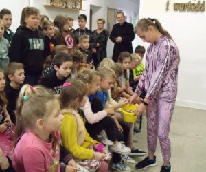 Członkini zarządu Samorządu Uczniowskiego częstuje cukierkami chłopców i pozostałe dzieci z okazji ich święta