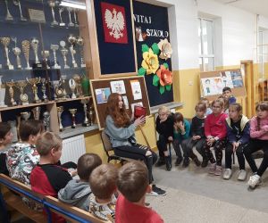 Uczennica pokazuje dzieciom książkę, którą wybrała dla nich do czytania