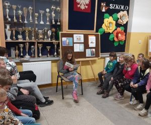 Uczennica piątej klasy czyta bajkę młodszym uczniom