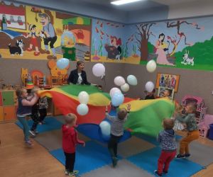 Przedszkolaki z wychowawczynią podrzucają balony na kolorowej chuście animacyjnej