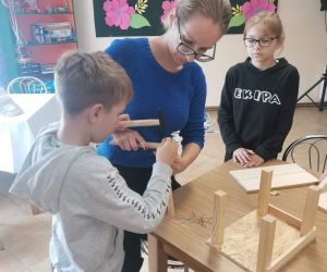 Na zdjęciu widoczne są trzy osoby montujące karmnik dla ptaków.