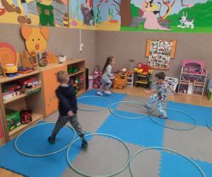 Przedszkolaki pokonują tor przeszkód ułożony na dywanie