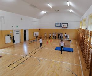 Uczniowie klas młodszych pokonują tor przeszkód w sali gimnastycznej