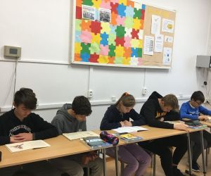 Młodzież z klasy ósmej siedzi w ławkach i czyta książki