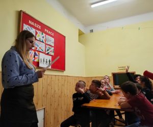 Dzieci razem z osobą prowadzącą zajęcia, w klasie.