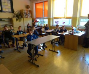 Dzieci razem z osobą prowadzącą zajęcia, w klasie.