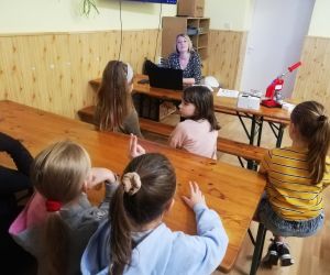 Dzieci razem z osobą prowadzącą zajęcia, w klasie.