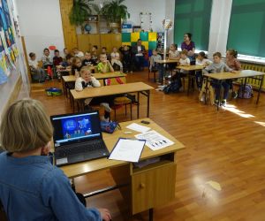 Dzieci razem z osobą prowadzącą zajęcia, w klasie.