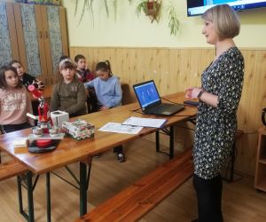 Dzieci razem z osobą prowadzącą zajęcia, w klasie.