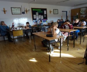 Dzieci razem z osobą prowadzącą zajęcia, w klasie.