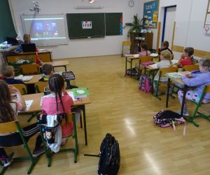 Dzieci razem z osobą prowadzącą zajęcia, w klasie.