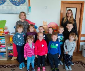 Dzieci razem z osobą prowadzącą zajęcia, w klasie.
