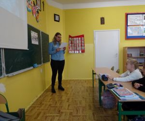 Dzieci razem z osobą prowadzącą zajęcia, w klasie.