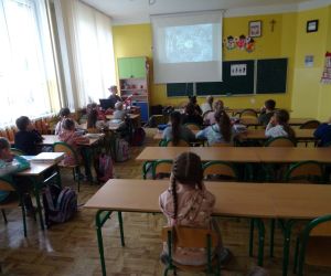 Dzieci razem z osobą prowadzącą zajęcia, w klasie.