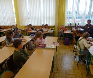 Dzieci razem z osobą prowadzącą zajęcia, w klasie.