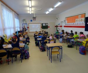 Dzieci razem z osobą prowadzącą zajęcia, w klasie.