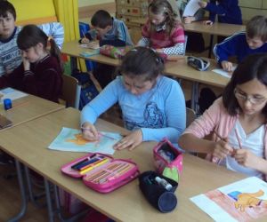 Dzieci w szkole, siedzą w ławkach, wykonują prace plastyczne w trakcie zajęć lekcyjnych