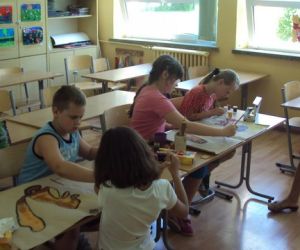 Nauczyciel prowadzący lekcje, dzieci wykonują prace plastyczne