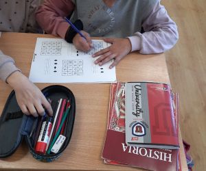 Uczennica rozwiązuje zadania z kodowania na kartce