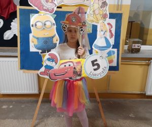 Uczennica w kolorowej spódniczce trzyma ozdobną ramkę do zdjęć