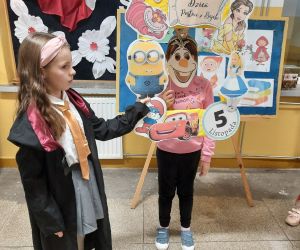 Dziewczynka w stroju Małej Czarodziejki z Harrego Pottera trzyma ramkę dziewczynce w masce Olafa