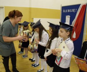 Przedstawicielka Rady Rodziców rozdaje pierwszoklasistom upominki