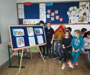 Uczniowie siedzą obok gazetki przygotowanej z okazji Dnia Praw Dziecka