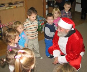 Dzieci z Mikołajem, stoją w klasie lekcyjnej. W tle widać materiały edukacyjne oraz zabawki.