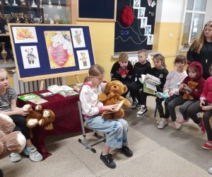 Dziewczynka czyta młodszym dzieciom bajkę o misiu