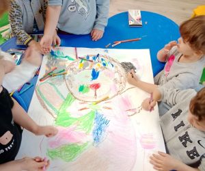 Na zdjęciu widoczne są dzieci pracujące wspólnie przy jednym rysunku misia.