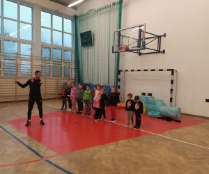 Trener pokazuje ćwiczenie, a dzieci słuchają