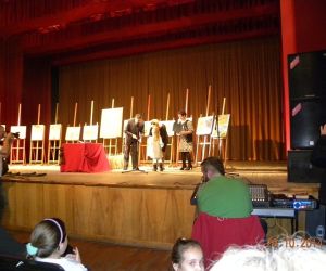 Scena na niej dziecko oraz dorośli, w tle sztalugi.