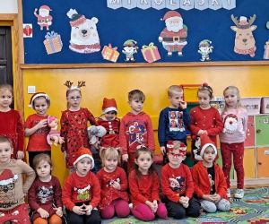 Dzieci ubrane w czerwone stroje czekają w sali na wizytę Mikołaja