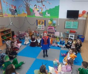 Przedszkolaki siedzą na dywanie w kole. W kole znajduje się dziewczynka